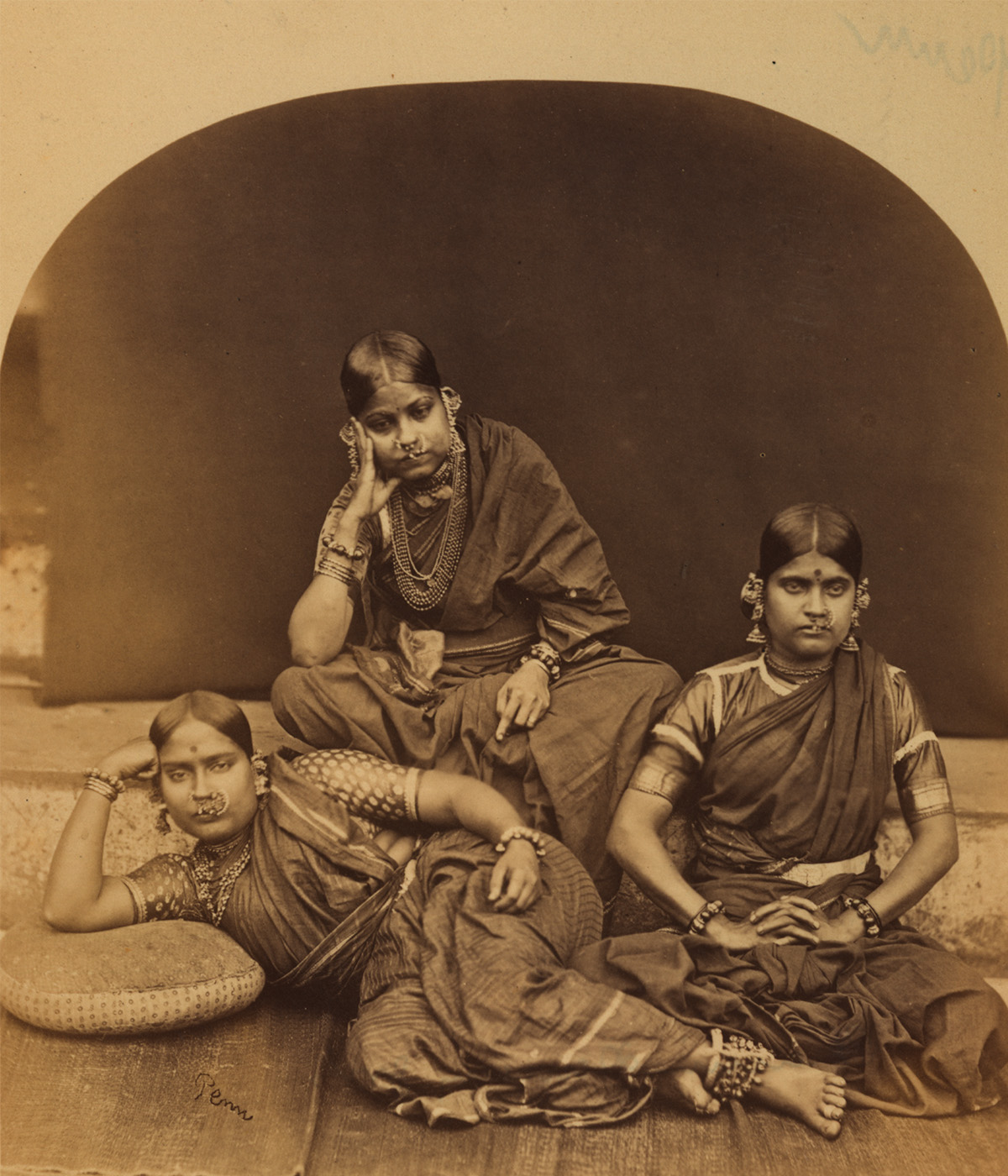 A sepia-toned photograph of three women, who were probably dancers, seated and reclining together.